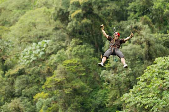 A man rides a zipline over the hills of the Ozark Mountains