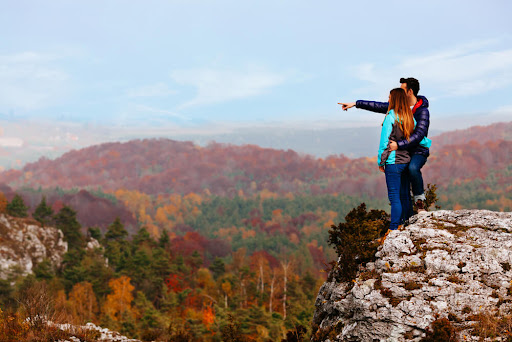 People on a ridge overlooking the fall colors of the Ozark Mountains.
