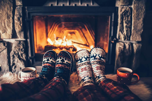 Feet in fuzzy slippers sitting in front of a cozy fire, enjoying Christmas season in Eureka Springs.

